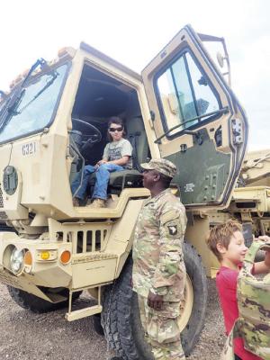 Eight-year-old Jaden Alexander takes the driver’s seat of a military tow truck as Army Specialist LeDarius Johnson of Boston, MA looks on during Saturday’s Touch a Truck event held at the Alpine Public Library. Photo by Kerry Laird
