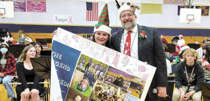 Alpine High School senior Nancy Hinojosa shows off the signed poster on behalf of the Buck Band to outgoing band Director Chuck Wilson at the Christmas band concert Dec. 16 in the high school gym. Avalanche photo by Roxanne Hill