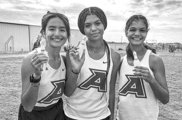 Runnin’ Buck girls relay team members Alexa Renteria, Danica Mulholland, and Megan Struthers take a break during the Derek Hernandez Memorial Relay in Andrews on Aug. 20.