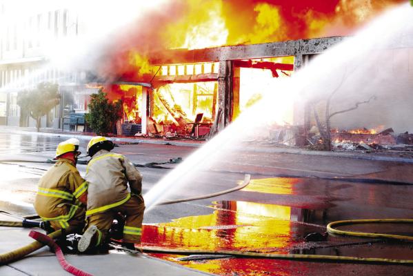 Firefighters aim a water hose at ground level on Sunday while attempting to extinguish the large structure fire that broke out in downtown Alpine. Photo courtesy of Bill Elliott