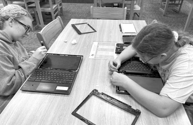 Eighth-grade library aids at Alpine Middle School work on replacing screens on Chromebooks that students use.