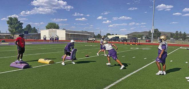 AHS Defensive Coordinator and Linebacker Coach Jerry Dominguez works with his linebackers on a drill called “read drill,” where they work on base blocks they would see in a game. Alpine Buck David Baca is the player in motion, while A.J. Llanez watches and awaits his turn. Courtesy Photo