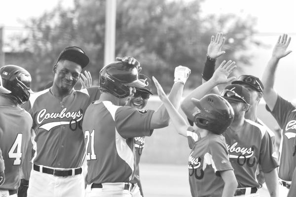 The team congratulates Hunter Reid as he adds yet another run to the Cowboy’s total. Photo by Julie Meyer