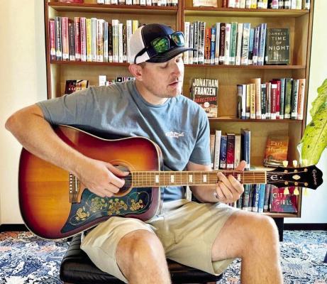 Matt Payne is pictured here strumming a guitar donated by the Marathon Songwriters Festival creator, Drew Kennedy. Kennedy donated it to the Marathon Public Library for all those interested in learning a new instrument or just checking out a different set of strings to hone their craft on. Photo courtesy of MPL