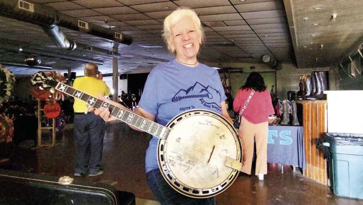 Penny Davis proudly shows off the autographed banjo that once belonged to Landon Miller of the bluegrass band Triple L. With signatures from the entire Miller family, this banjo hit a high note at the Big Bend Bluegrass Festival auction, where Sharon Haney plucked it as the winning bidder.