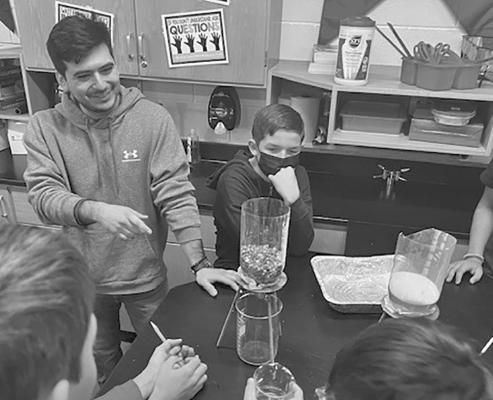 A Sul Ross Student Teacher helps seventh grade science students learn about the permeability of different types of soil.