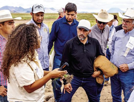 Borderlands Research Institute student Asia Cornelius shows field trip attendees from the Society for Range Management’s annual meeting the root structures of blue grama as she discusses its symbiotic relationship with fungi. Photo courtesy of BRI