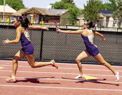 Neveah Carrasco reaches back towards fellow runner Naida Morris last Saturday in Kermit during the 4x200-meter relay at the Area track meet. Photo by Alice Saunders