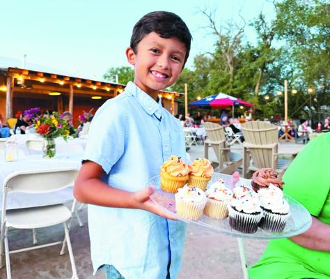 Cristiano Diaz, the son of the Sunshine House’s Executive Director, Sylvana Diaz, helps out at their Wild West Night on Saturday by distributing cupcakes to those who attended the annual fundraiser. Photo by Sylvana Diaz