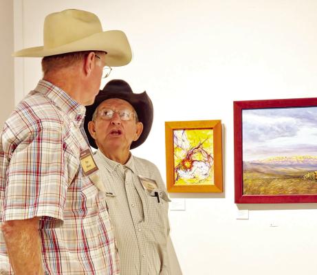 Trappings of Texas exhibiting artists Tim Oliver and Mike Capron discuss the merits of some of the artwork exhibited at the Museum of the Big Bend on Saturday. Photo by Kara Gerbert