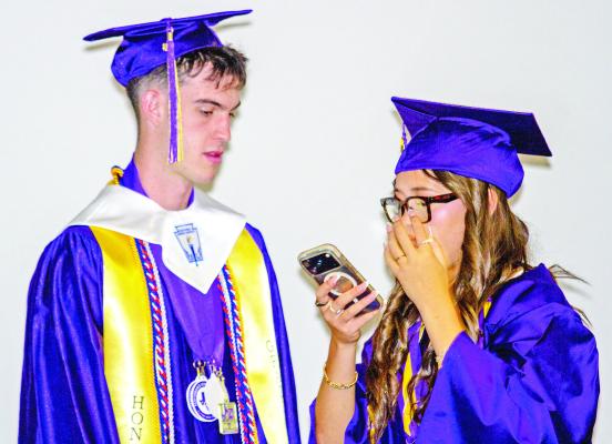 Jack Juett and Naida Morris confer over something on her phone as they prepare to walk into the gym at the Pete P. Gallego Center last Friday night to receive their diplomas. Photo by Kara Gerbert
