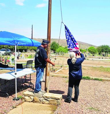 Martin Sandate and Candy Whyman hoist the colors during Saturday’s Memorial Day celebration fundraiser hosted by the Holy Angels Cemetery Association. Members of the American Legion Post #79 placed flags upon fallen service members’ graves and were a part of other ceremony activities. Photo by Lea Catano