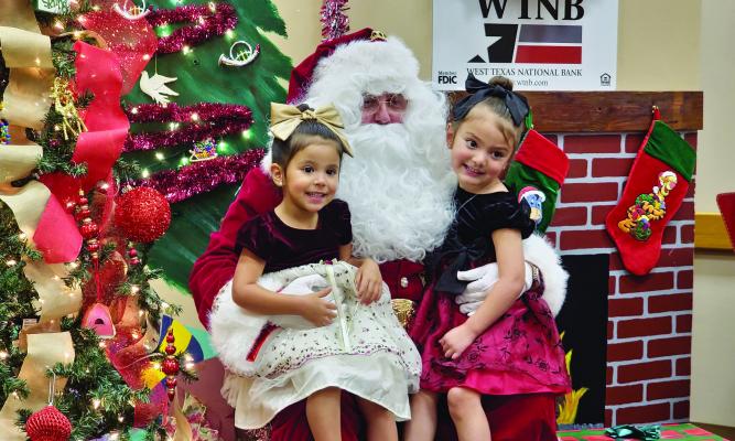 Aurora and Catalina Baeza visited with Jolly Ol’ St. Nick last Wednesday afternoon when he stopped at West Texas National Bank to talk to kids and ask what they wanted for Christmas. Photo by Kara Gerbert