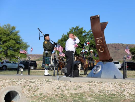 Alpine Volunteer Fire Department Chief James Etchison salutes the 9/11 memorial after placing the wreath during last Friday’s memorial ceremony honoring those who fell during the terrorist attacks in 2001. He is accompanied by a piper from the U.S. Border Patrol drum and pipe corps. Courtesy Photo