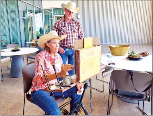 Alice Leese, the premier artist for the 2023 Trappings of Texas, works on a painting on the patio of the Museum of the Big Bend’s Emmett and Miriam McCoy Building while fellow artist Troy Menix looks on. Photo by Kara Gerbert