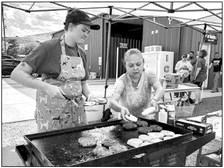 Kat Hendrick cooks burger patties for the Alpine Humane Society’s fundraiser last Friday evening at Skelton’s Runway. Assisting Hendrick is Martha Medina, a volunteer for the humane society. Photo by J.T. Maroney