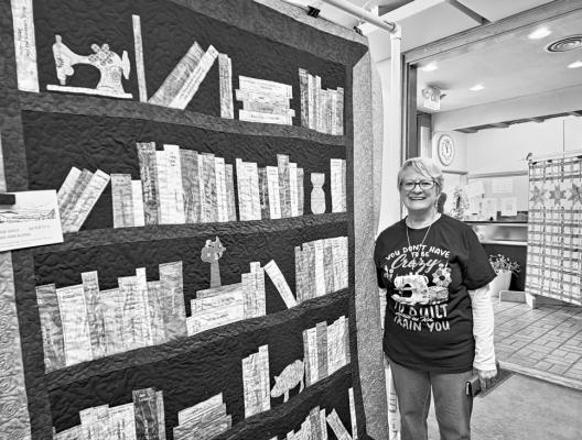 Robbie Ann Burns stands beside one of several quilts she had on display at the annual quilt show this past Saturday. Burns’ quilt is entitled “My Story on a Bookshelf” where she commented, “I don’t believe any book should be banned. I think we can learn something from all of them.” The quilt listed many of the books Burns had read over the years, and although she’d had several offers to buy it, she turned them down. Photo by Kara Gerbert