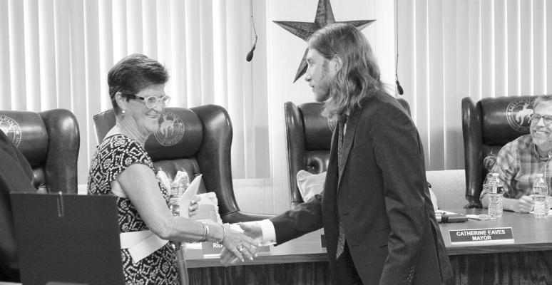 Reagan Stone and Judy Stokes shake hands after Stone is sworn in as Ward 1 City Council member, taking Stoke’s vacated place after the recent election. Photo by Joh Covington