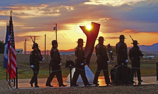 The sun rises through the top of the 9/11 memorial as United States Border Patrol officers hold their annual ceremony honoring those Americans who lost their lives on that fateful morning in 2001. The memorial is held at the USBP Alpine station in front of the mangled piece of iron from the Twin Towers Photo by Matt Walter