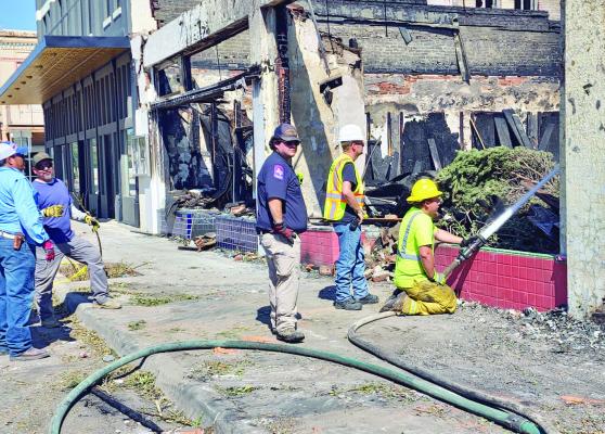 Alpine Volunteer firefighter Ethan Sullivan sprays water into the ruins of Judy’s Bread and Breakfast to continue extinguishing lingering hot spots after last Sunday’s devastating fire as fellow Alpine firefighter David Neet and Terlingua Fire/EMS representative Jared Thomason along with two Brewster County employees, Merced Hernandez and Israel Natera look on. Photo by Kara Gerbert