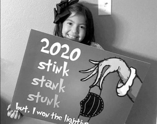 Taylor Ramirez, 9, holds the yard sign that a neighbor won in the 2020 lighting contest. Courtesy photo