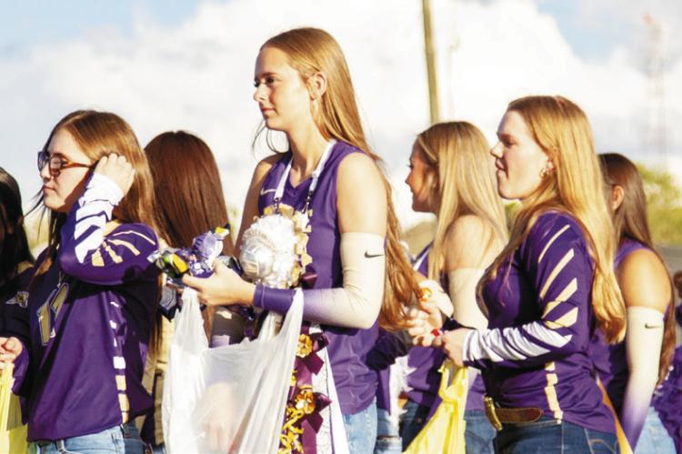 The Lady Buck volleyball team holds sacks of candy that they throw to the crowd during this year’s Homecoming parade.